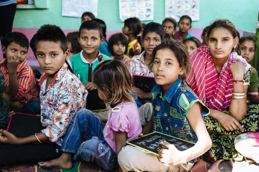 Children sitting together in class holding slates eager to learn